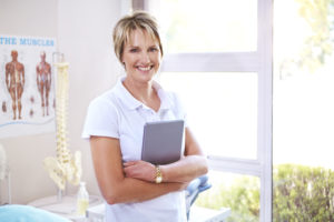 GettyImages-562873443 Portrait confident physical therapist with digital tablet in examination room